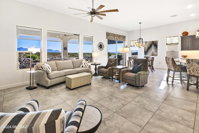 living area with light tile patterned floors, baseboards, ceiling fan with notable chandelier, and visible vents