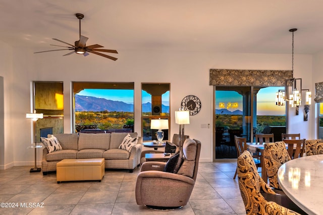 tiled living room with baseboards, a mountain view, and ceiling fan with notable chandelier