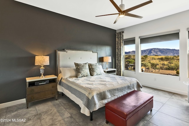 bedroom with baseboards, a ceiling fan, and a mountain view