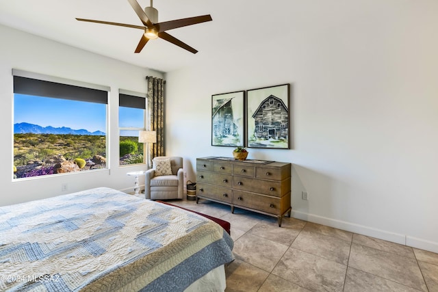 tiled bedroom with baseboards, a ceiling fan, and a mountain view