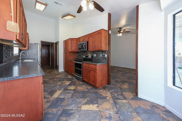 kitchen featuring ceiling fan, sink, stainless steel appliances, backsplash, and high vaulted ceiling