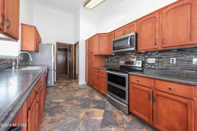 kitchen featuring stainless steel appliances, tasteful backsplash, sink, and a towering ceiling