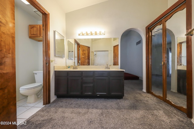 bathroom featuring vanity, tile patterned floors, vaulted ceiling, toilet, and a shower