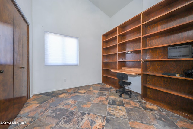 home office featuring a wall mounted air conditioner, built in desk, and vaulted ceiling