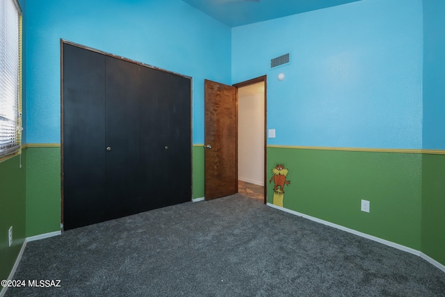 unfurnished bedroom featuring a closet and dark colored carpet