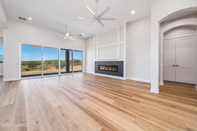 67970 E Madison Rd, Oracle, AZ 85623 - unfurnished living room featuring ceiling fan, high vaulted ceiling, a glass covered fireplace, arched walkways, and light wood-type flooring