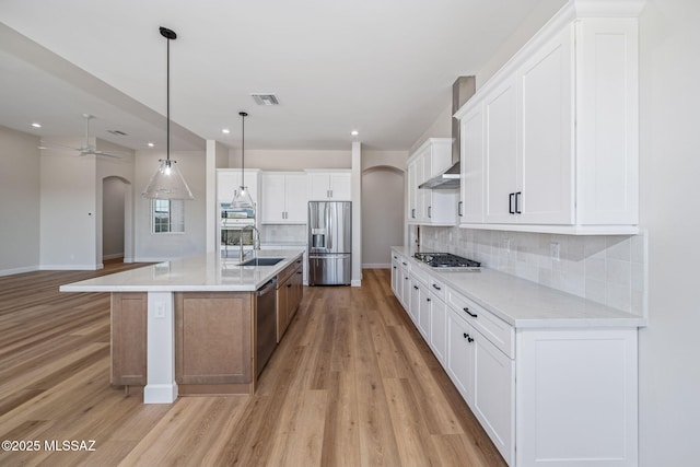 67970 E Madison Rd, Oracle, AZ 85623 - kitchen with arched walkways, appliances with stainless steel finishes, light wood-style floors, tasteful backsplash, and open floor plan