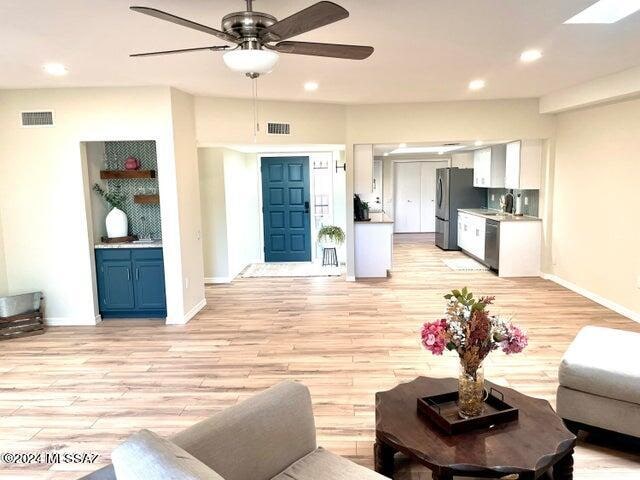 living room with light hardwood / wood-style flooring, sink, and ceiling fan