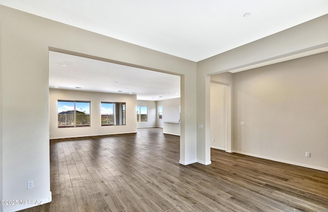 8257 S Silver Oak Dr, Tucson, AZ 85747 - unfurnished living room featuring dark wood-style flooring and baseboards