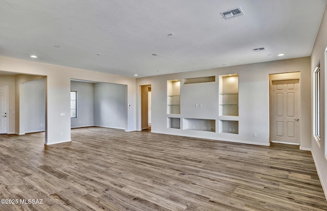 8257 S Silver Oak Dr, Tucson, AZ 85747 - unfurnished living room with baseboards, wood finished floors, recessed lighting, and built in features