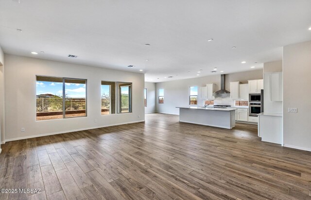 8257 S Silver Oak Dr, Tucson, AZ 85747 - unfurnished living room with healthy amount of natural light, recessed lighting, dark wood-style flooring, baseboards, and a sink