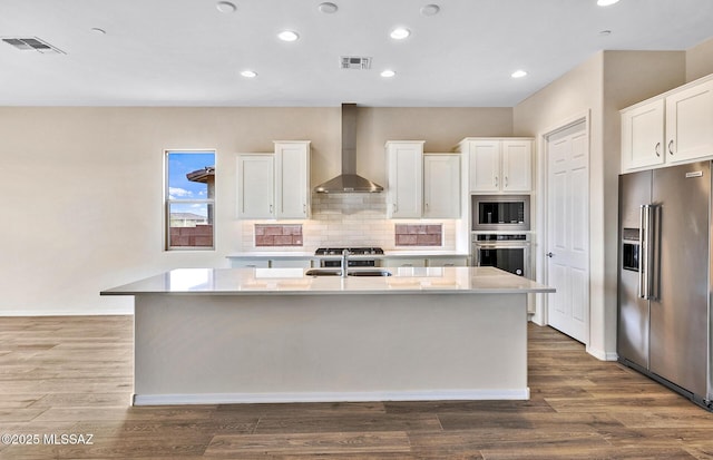 8257 S Silver Oak Dr, Tucson, AZ 85747 - kitchen with stainless steel appliances, wall chimney exhaust hood, a sink, an island with sink, and white cabinetry