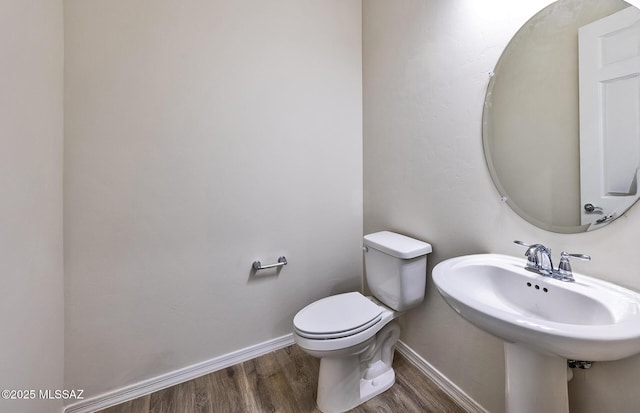 8257 S Silver Oak Dr, Tucson, AZ 85747 - half bathroom featuring wood finished floors, toilet, baseboards, and a sink