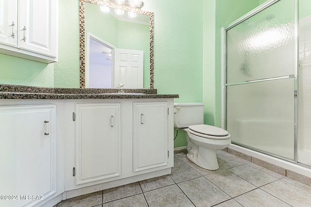 bathroom featuring vanity, toilet, a shower with door, and tile patterned floors