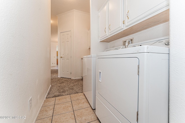 clothes washing area with light carpet, washing machine and clothes dryer, and cabinets