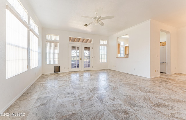 spare room featuring a healthy amount of sunlight, ceiling fan, and french doors