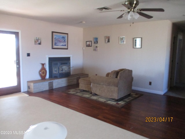 living room with plenty of natural light, dark hardwood / wood-style flooring, and a wood stove