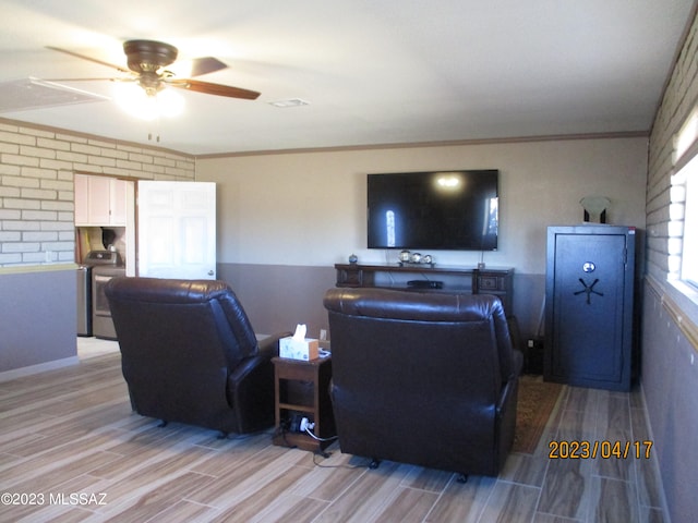 living room featuring ceiling fan, light hardwood / wood-style flooring, ornamental molding, and washer / dryer