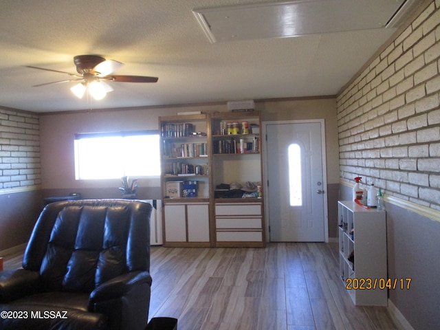 kitchen featuring light hardwood / wood-style flooring, ceiling fan, brick wall, and a textured ceiling