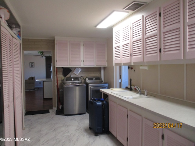 laundry room featuring separate washer and dryer, sink, and cabinets