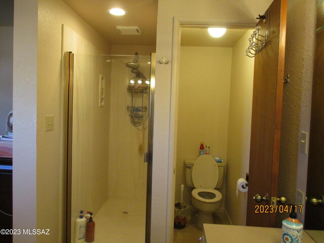 bathroom with toilet and a shower with door