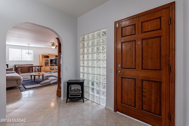 tiled entrance foyer with ceiling fan, a textured ceiling, and a wood stove