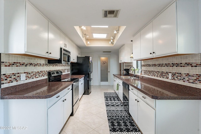 kitchen featuring dark countertops, black appliances, a raised ceiling, and a sink