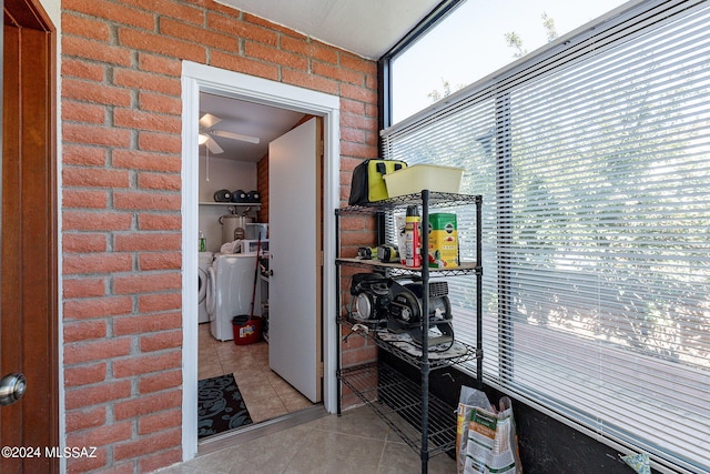 interior space with independent washer and dryer, brick wall, and light tile patterned floors