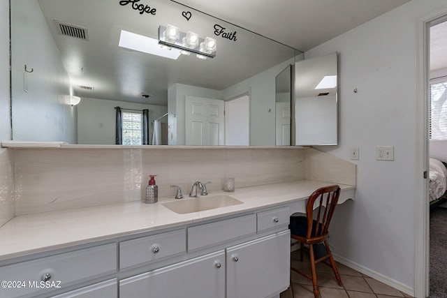 bathroom featuring a skylight, vanity, tasteful backsplash, a shower, and tile patterned flooring