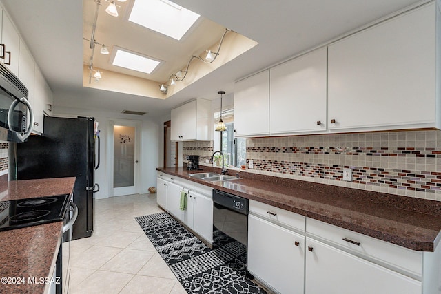 kitchen with a tray ceiling, black dishwasher, dark countertops, backsplash, and a sink