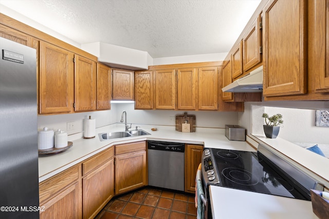 kitchen with stainless steel appliances, dark tile patterned flooring, sink, and a textured ceiling