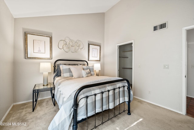 carpeted bedroom with a spacious closet and vaulted ceiling