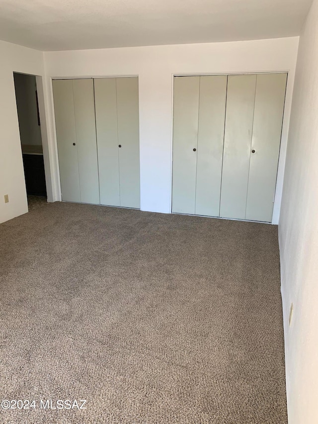 unfurnished bedroom with carpet floors and multiple closets