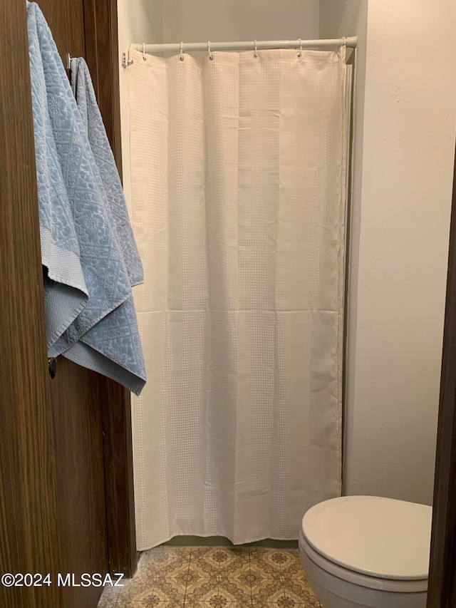 bathroom featuring a shower with curtain, tile patterned floors, and toilet