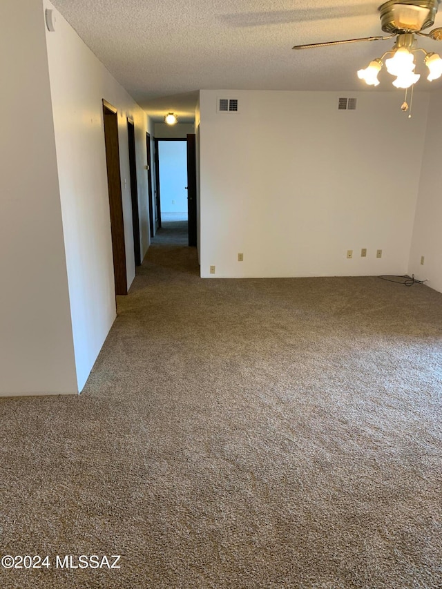 carpeted spare room featuring ceiling fan and a textured ceiling