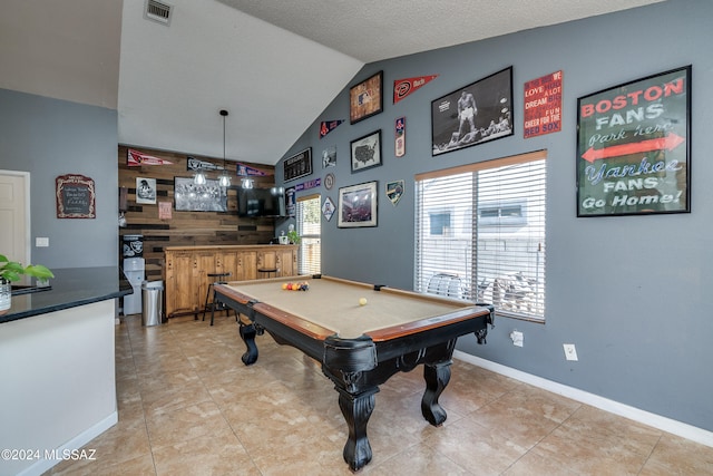 playroom featuring lofted ceiling, bar, wooden walls, billiards, and a textured ceiling