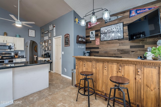 kitchen featuring a textured ceiling, hanging light fixtures, ceiling fan, stainless steel appliances, and white cabinets