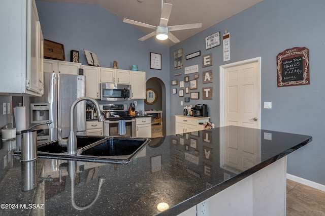 kitchen with appliances with stainless steel finishes, white cabinetry, ceiling fan, dark stone countertops, and light tile patterned floors