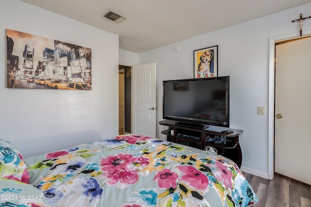 bedroom with a textured ceiling and dark hardwood / wood-style flooring