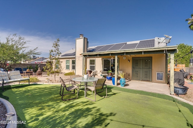 rear view of property with solar panels and a patio area