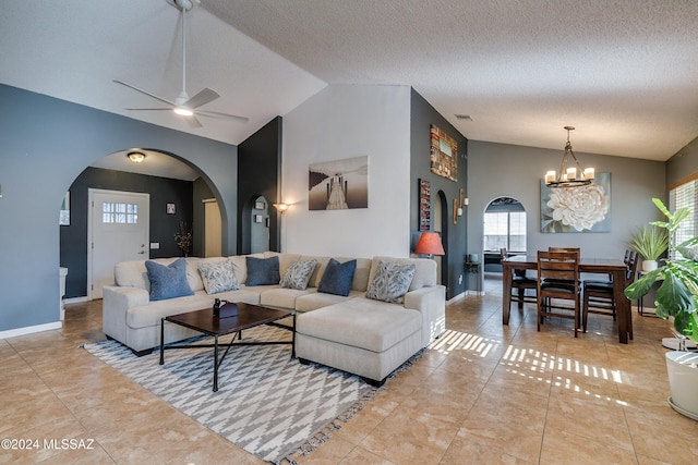 tiled living room featuring lofted ceiling, a textured ceiling, and ceiling fan with notable chandelier