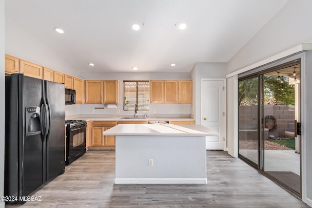 kitchen with lofted ceiling, a center island, and black appliances