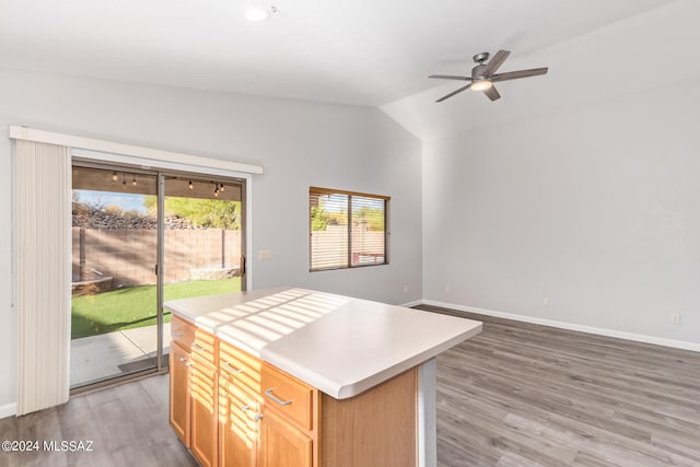 kitchen with hardwood / wood-style floors, vaulted ceiling, a center island, and ceiling fan