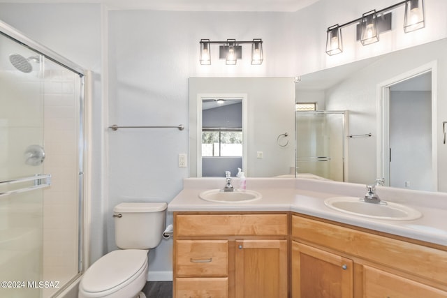 bathroom with vanity, toilet, and a shower with door