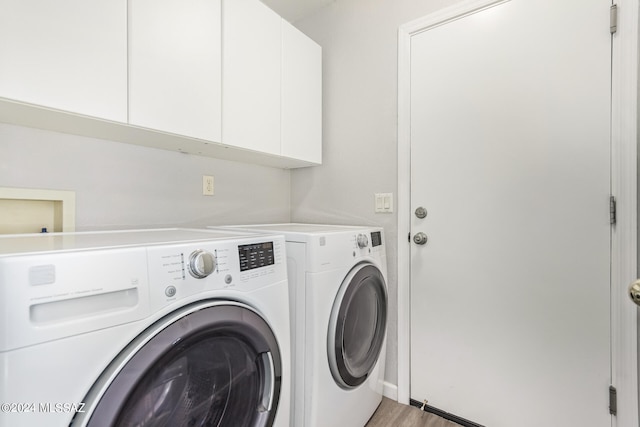 laundry room featuring washer and clothes dryer, hardwood / wood-style floors, and cabinets