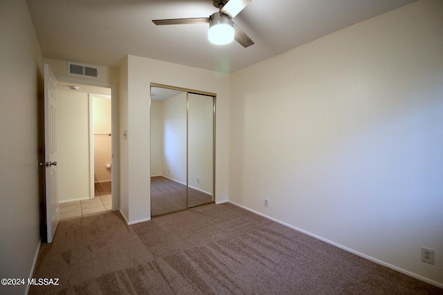 unfurnished bedroom featuring ceiling fan, light colored carpet, and a closet