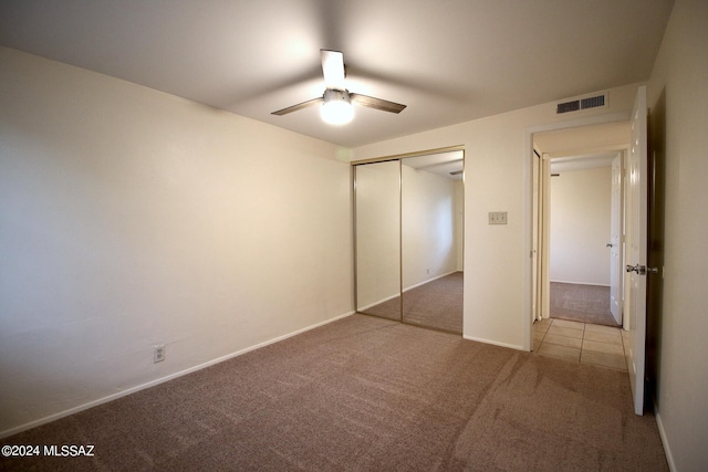 unfurnished bedroom featuring a closet, light colored carpet, and ceiling fan