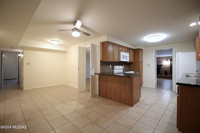 kitchen featuring white appliances, light tile patterned floors, kitchen peninsula, and ceiling fan