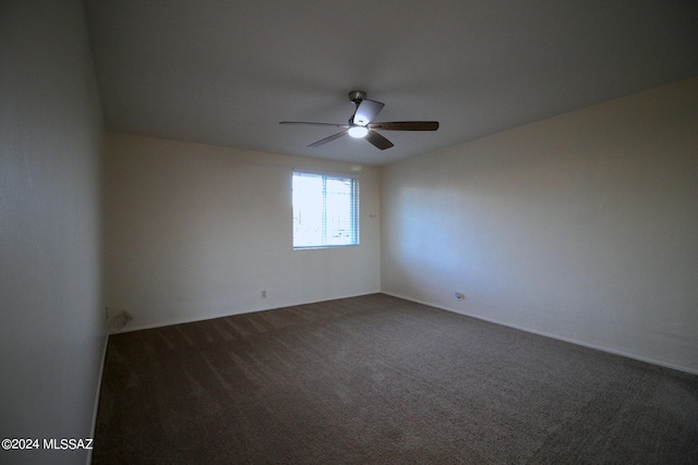 empty room featuring ceiling fan and dark carpet