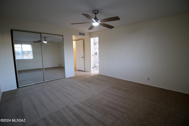 unfurnished bedroom with a closet, light colored carpet, and ceiling fan